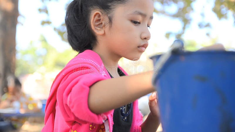 Κλείστε το αυξημένο ασιατικό μικρό κορίτσι που χρωματίζει την κούκλα
