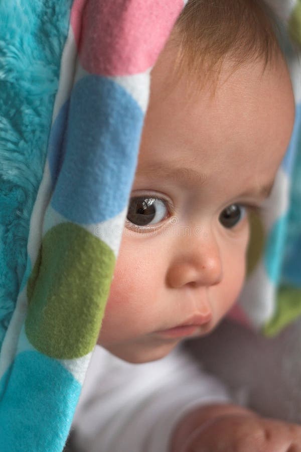 Image of baby peeking out from under a blanket. Image of baby peeking out from under a blanket