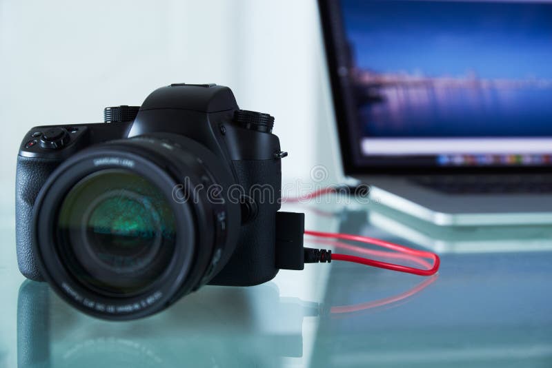 Κάμερα φωτογραφιών DSLR που δένεται στο φορητό προσωπικό υπολογιστή με το καλώδιο USB στοκ φωτογραφία Κάμερα φωτογραφιών DSLR που δένεται στο φορητό προσωπικό υπολογιστή με το καλώδιο USB στοκ φωτογραφία