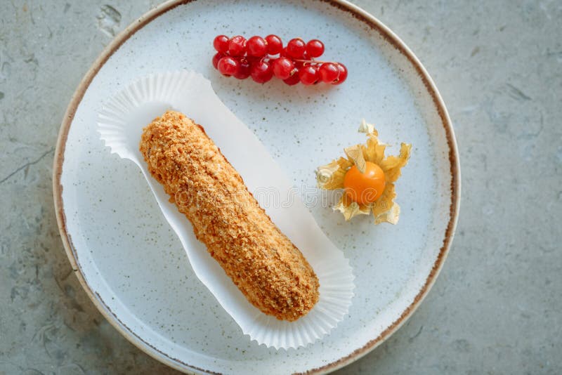 Κέικ ECLAIR σε ένα πιάτο με τη χρυσή περιποίηση που διακοσμείται με τα εσπεριδοειδή και τα μούρα στοκ φωτογραφίες Κέικ ECLAIR σε ένα πιάτο με τη χρυσή περιποίηση που διακοσμείται με τα εσπεριδοειδή και τα μούρα στοκ φωτογραφίες