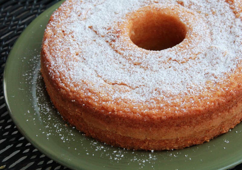 A yellow pound cake dusted with sugar on a green plate. A yellow pound cake dusted with sugar on a green plate.