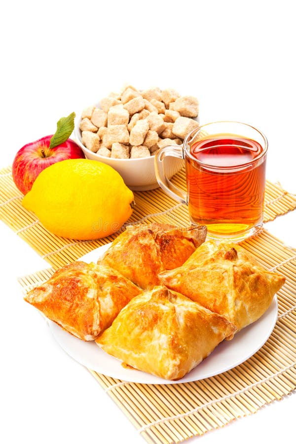 Κέικ σε ένα πιάτο, μαύρο τσάι, λεμόνι, κόκκινο μήλο, καφετιά ζάχαρη στο θόριο στοκ εικόνα