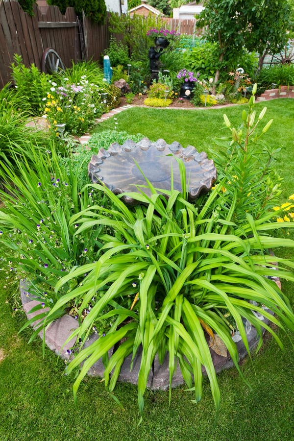 A gorgeous backyard garden, featuring a center bed of perennials around a bird bath. A gorgeous backyard garden, featuring a center bed of perennials around a bird bath.