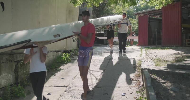 Κίεβο UA, 31-07-2019 Αγόρια έφηβοι με προπονητή που μεταφέρουν αθλητικό σκάφος στο νερό