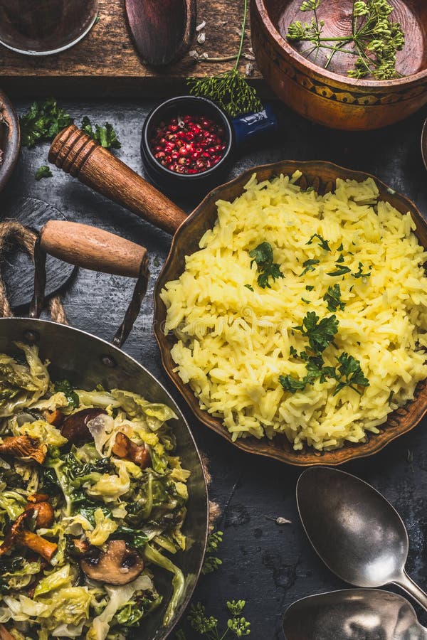 Κίτρινο πιάτο ρυζιού με το μαγειρευμένο τεμαχισμένο λάχανο και μανιτάρια στο αγροτικό υπόβαθρο κουζινών, τοπ άποψη