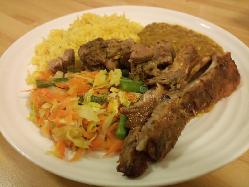 Κίτρινο χρωματισμένο ρύζι pilau με τα juicy πλευρά και τις φακές στοκ εικόνα Κίτρινο χρωματισμένο ρύζι pilau με τα juicy πλευρά και τις φακές στοκ εικόνα