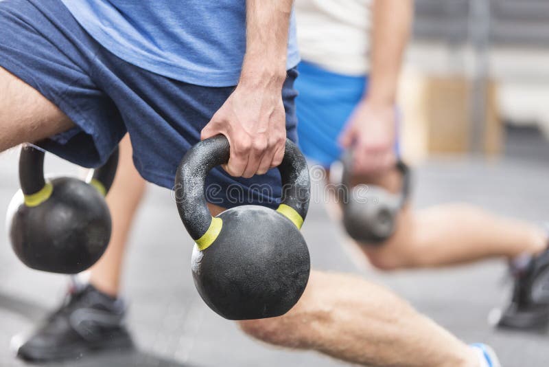 Cropped image of men lifting kettlebells at crossfit gym. Cropped image of men lifting kettlebells at crossfit gym