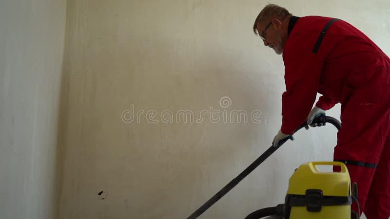 καθαρισμός κατά τις ανακαινίσεις στο νέο κτίριο. ηλικιωμένος εργαζόμενος σε αίθουσες κενή βάση τσιμεντένιο δάπεδο με βιομηχανική