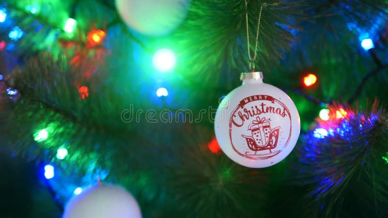 καλά χριστούγεννα τίτλος για τη λευκή μπάλα στο χριστουγεννιάτικο δέντρο. χριστουγεννιάτικο φόντο με γαρίφαλο και μπάλα.