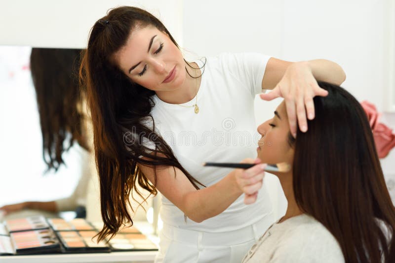 Καλλιτέχνης Makeup που αποτελεί μια αφρικανική νέα γυναίκα σε ένα κέντρο ομορφιάς στοκ φωτογραφία με δικαίωμα ελεύθερης χρήσης Καλλιτέχνης Makeup που αποτελεί μια αφρικανική νέα γυναίκα σε ένα κέντρο ομορφιάς στοκ φωτογραφία με δικαίωμα ελεύθερης χρήσης
