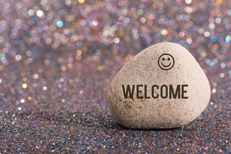 A white stone with words welcome and smile face on color glitter boke background. A white stone with words welcome and smile face on color glitter boke background