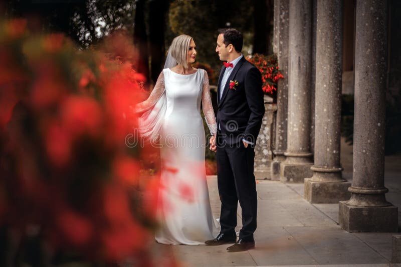 Καλό ζεύγος των newlyweds - νύφη και νεόνυμφος που περπατούν γύρω από ένα παλαιό όμορφο παλάτι πετρών υπαίθρια στοκ εικόνες