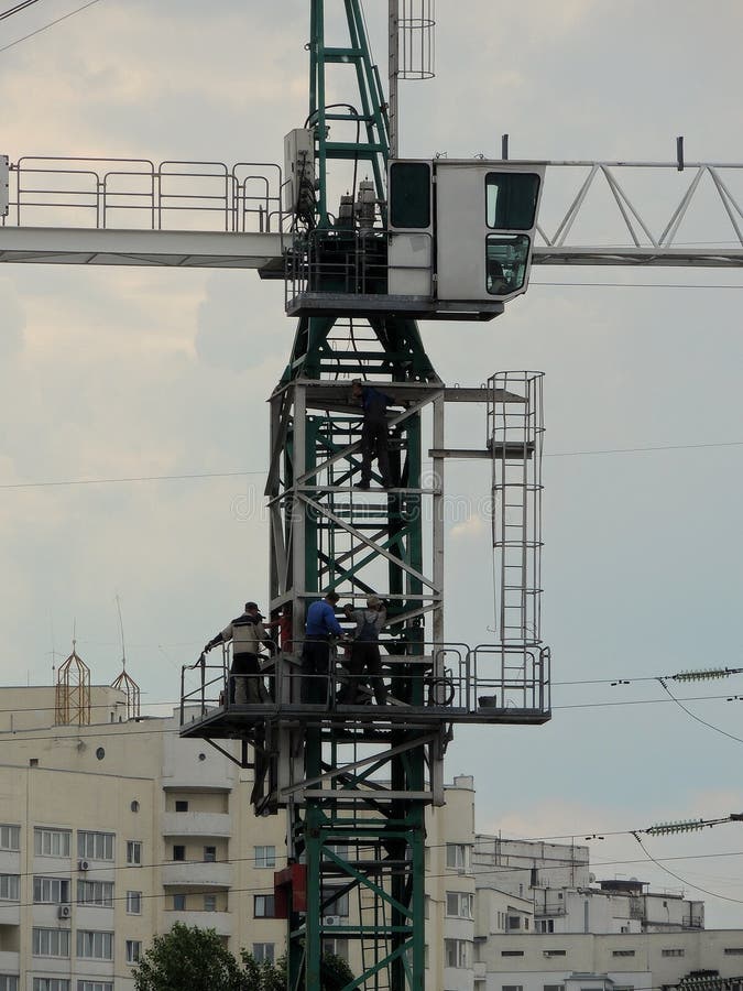 Καμπίνα του γερανού οικοδόμησης μεγάλου υψομέτρου με τους εργαζομένους πέρα από τα κτήρια πόλεων στοκ εικόνα Καμπίνα του γερανού οικοδόμησης μεγάλου υψομέτρου με τους εργαζομένους πέρα από τα κτήρια πόλεων στοκ εικόνα