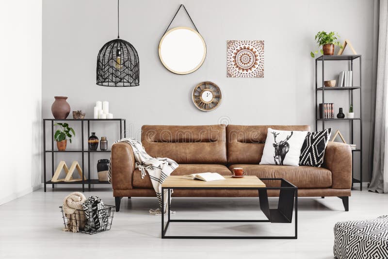 Leather sofa with pillows and blanket in the middle of elegant living room interior with metal shelves and modern coffee table, real photo. Leather sofa with pillows and blanket in the middle of elegant living room interior with metal shelves and modern coffee table, real photo