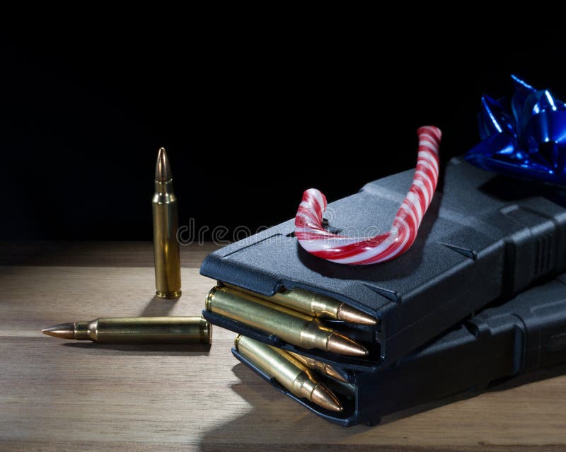 Blue bow and candy cane on two fully loaded polymer AR-15 magazines on a black background with room for text. Blue bow and candy cane on two fully loaded polymer AR-15 magazines on a black background with room for text