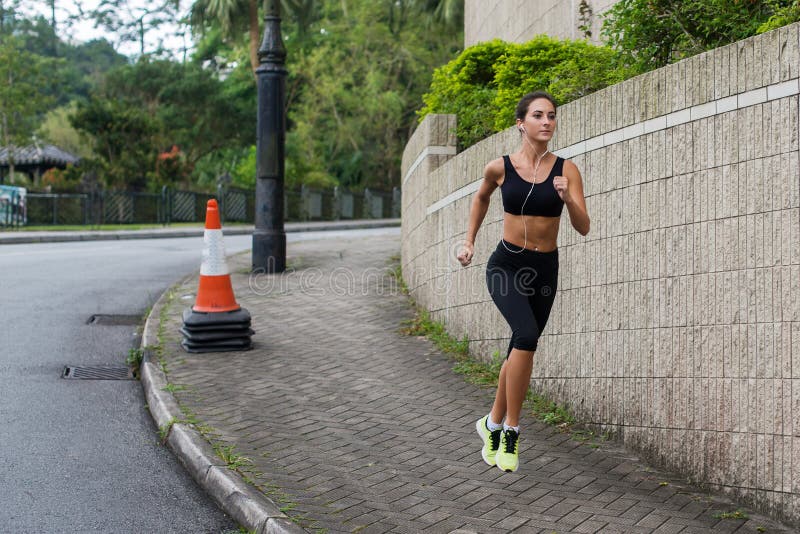 Κατάλληλο νέο θηλυκό jogger που στο πεζοδρόμιο στην προαστιακή περιοχή Όμορφο κορίτσι που επιλύει υπαίθρια στοκ φωτογραφία Κατάλληλο νέο θηλυκό jogger που στο πεζοδρόμιο στην προαστιακή περιοχή Όμορφο κορίτσι που επιλύει υπαίθρια στοκ φωτογραφία