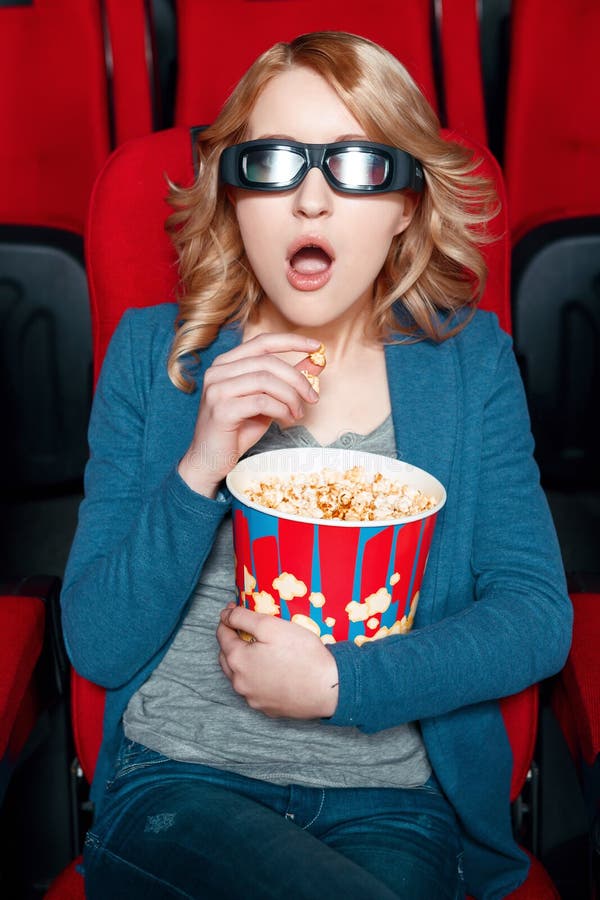 Κατάπληκτη γυναίκα στα γυαλιά που τρώει popcorn στοκ εικόνα