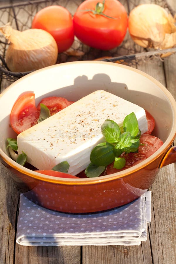 κατακόρυφη λήψη ενός μπολ με ελληνική σαλάτα με ντομάτα βασιλικό κρεμμύδι και φέτα σε ένα ξύλινο τραπέζι στοκ εικόνα με δικαίωμα ελεύθερης χρήσης