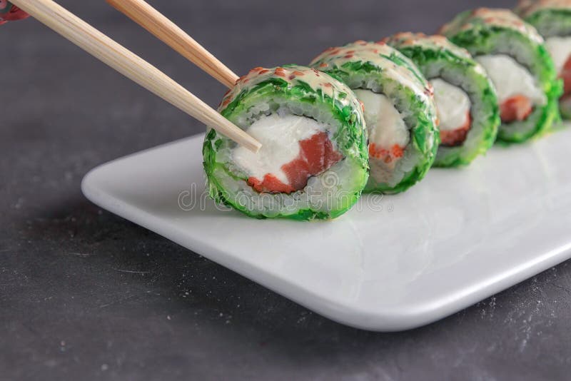Κατανάλωση των σουσιών με chopsticks Τα σούσια κινηματογραφήσεων σε πρώτο πλάνο κυλούν τα ιαπωνικά τρόφιμα στο εστιατόριο στοκ φωτογραφία με δικαίωμα ελεύθερης χρήσης Κατανάλωση των σουσιών με chopsticks Τα σούσια κινηματογραφήσεων σε πρώτο πλάνο κυλούν τα ιαπωνικά τρόφιμα στο εστιατόριο στοκ φωτογραφία με δικαίωμα ελεύθερης χρήσης