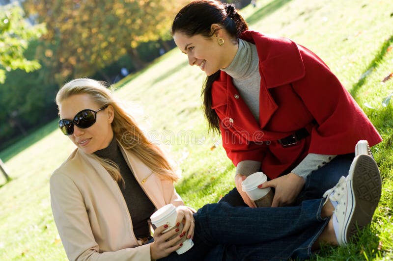 Two young women having coffee break together in park. Two young women having coffee break together in park