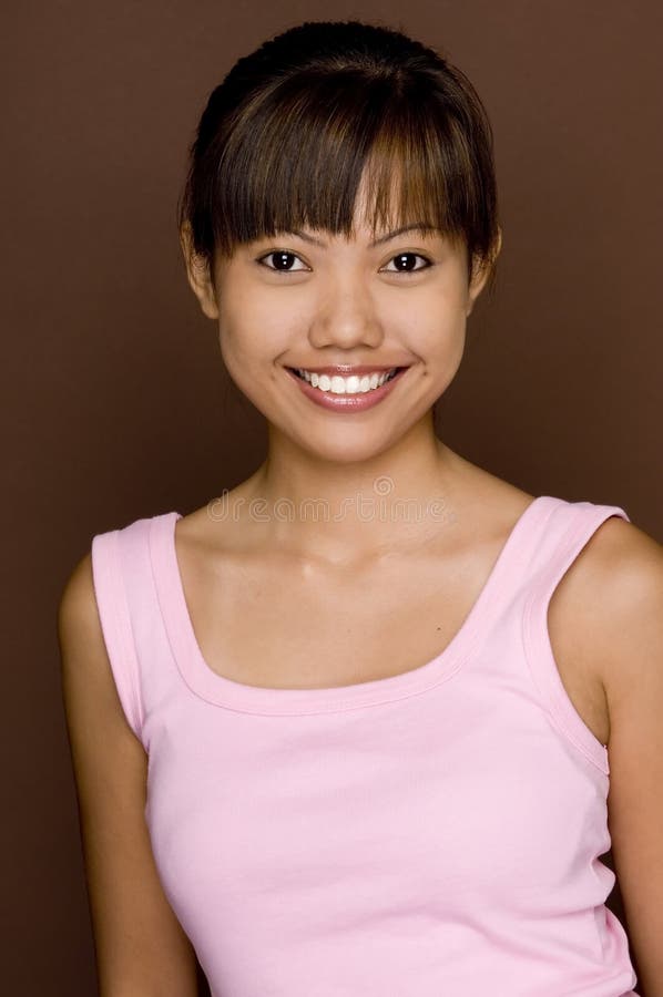 A cute young asian model in pink on brown background. A cute young asian model in pink on brown background
