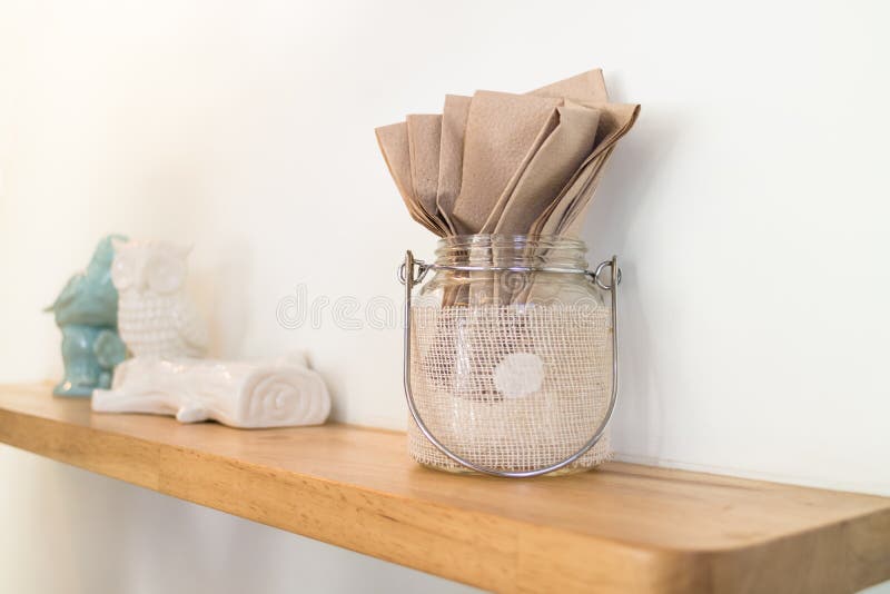 Καφετιά ανακυκλωμένη πετσέτα φραγμών στο βάζο γυαλιού στο ξύλινο ράφι