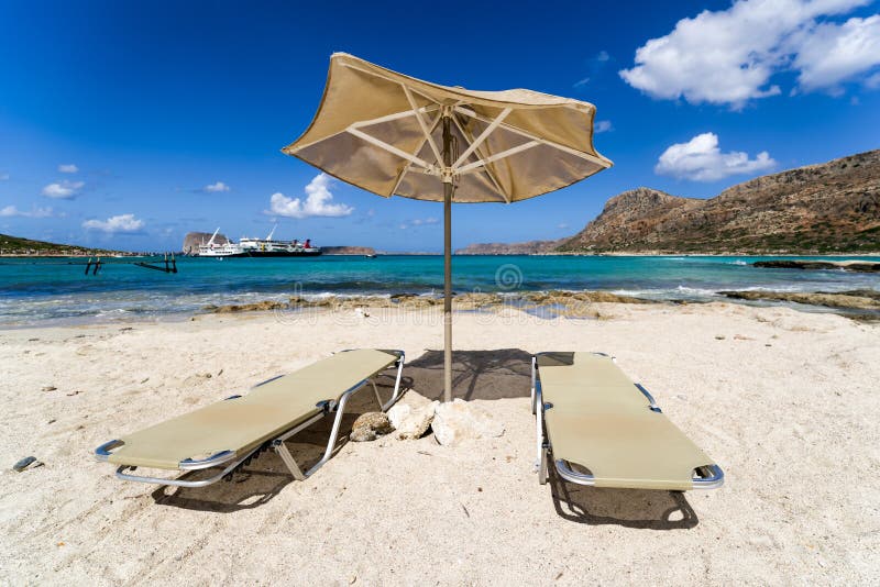 Κενός αργόσχολος κάτω από sunshade στην αμμώδη παραλία στοκ εικόνα με δικαίωμα ελεύθερης χρήσης Κενός αργόσχολος κάτω από sunshade στην αμμώδη παραλία στοκ εικόνα με δικαίωμα ελεύθερης χρήσης