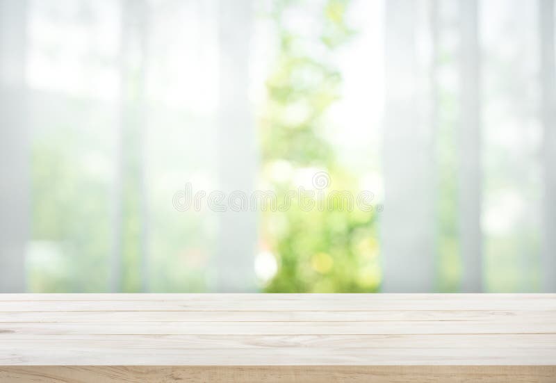 Κενός της ξύλινης επιτραπέζιας κορυφής στη θαμπάδα της κουρτίνας με την άποψη παραθύρων πράσινη από τον κήπο δέντρων