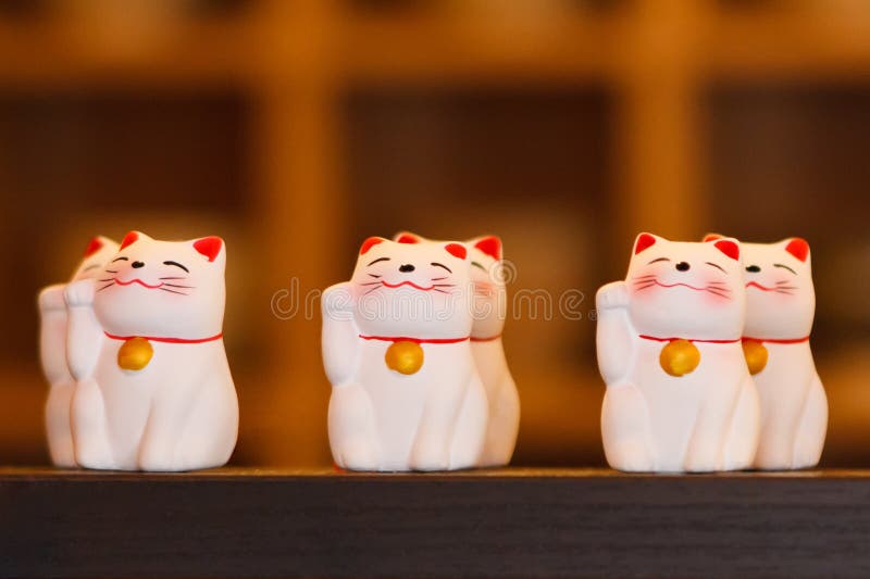 Κεραμικές κούκλες γατών Maneki Neko στο ξύλινο ράφι στοκ εικόνες Κεραμικές κούκλες γατών Maneki Neko στο ξύλινο ράφι στοκ εικόνες