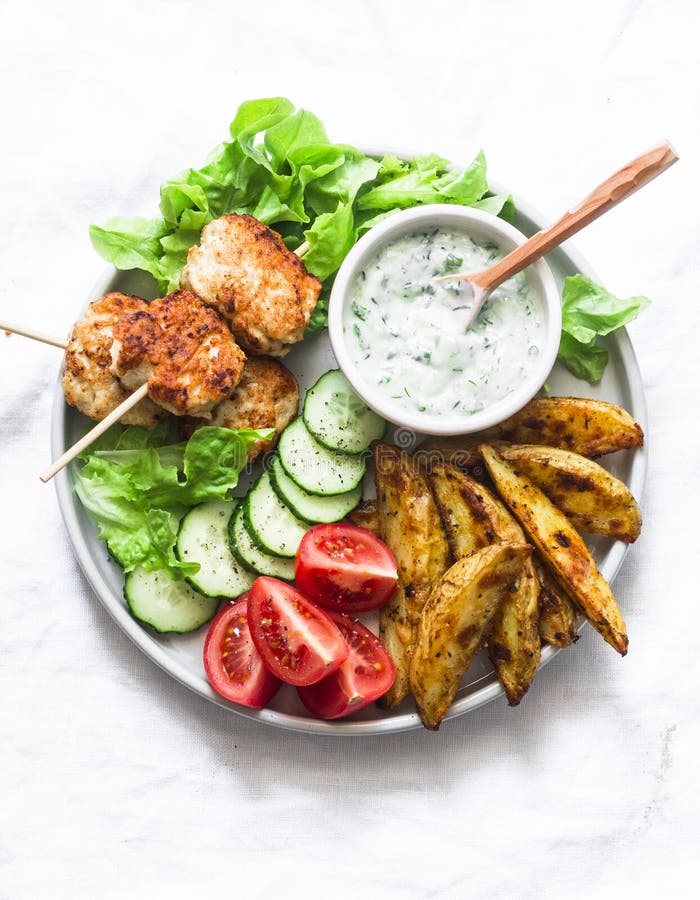 Κεφτή kebab, αγροτική ψημένη πατάτα, φρέσκα λαχανικά και σάλτσα χορταριών γιαουρτιού στο ελαφρύ υπόβαθρο, τοπ άποψη Θερινό πικ-νί στοκ φωτογραφία με δικαίωμα ελεύθερης χρήσης Κεφτή kebab, αγροτική ψημένη πατάτα, φρέσκα λαχανικά και σάλτσα χορταριών γιαουρτιού στο ελαφρύ υπόβαθρο, τοπ άποψη Θερινό πικ-νί στοκ φωτογραφία με δικαίωμα ελεύθερης χρήσης