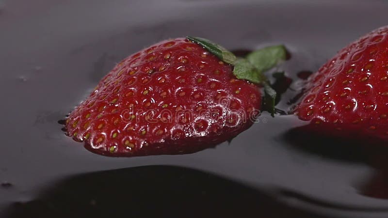 Κινηματογράφηση σε πρώτο πλάνο της εύγευστης φράουλας που περιέρχεται στο σιρόπι σοκολάτας