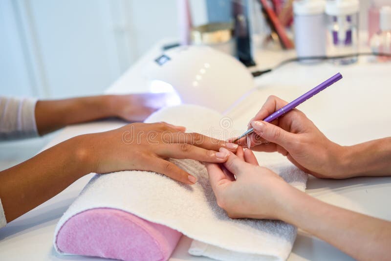 Κινηματογράφηση σε πρώτο πλάνο του beautician καρφιά γυναικών ` s ζωγραφικής το με μια βούρτσα μέσα στοκ εικόνα Κινηματογράφηση σε πρώτο πλάνο του beautician καρφιά γυναικών ` s ζωγραφικής το με μια βούρτσα μέσα στοκ εικόνα