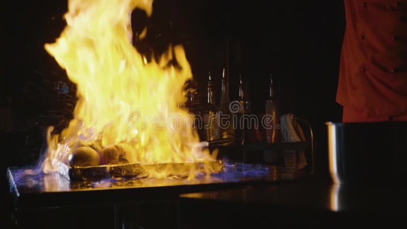 Κινηματογράφηση σε πρώτο πλάνο του αρχιμάγειρα που μαγειρεύει ένα κύριο πιάτο συμποσίου Τα λαχανικά και το κρέας με την πυρκαγιά απόθεμα βίντεο Κινηματογράφηση σε πρώτο πλάνο του αρχιμάγειρα που μαγειρεύει ένα κύριο πιάτο συμποσίου Τα λαχανικά και το κρέας με την πυρκαγιά απόθεμα βίντεο