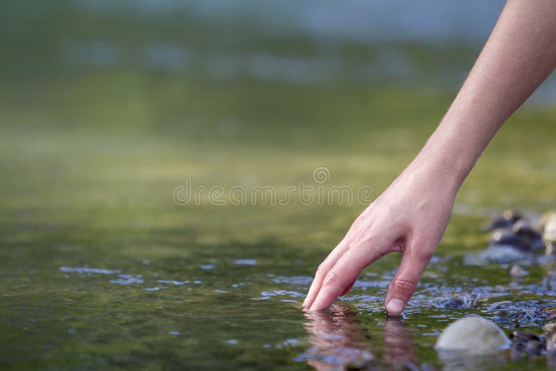 Close-up of beautiful white woman hand tenderly touching, scooping clean fresh sweet water on blurred green copy-space background. Tourism, active lifestyle, nature and pollution problems concept. Close-up of beautiful white woman hand tenderly touching, scooping clean fresh sweet water on blurred green copy-space background. Tourism, active lifestyle, nature and pollution problems concept.