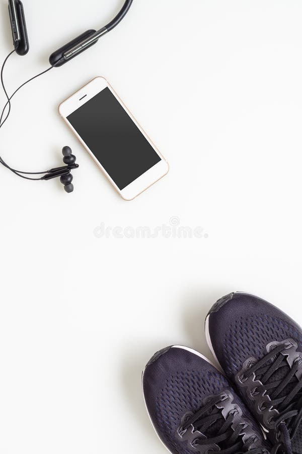Κινητό κινητό τηλέφωνο προτύπων με το ασύρματο ακουστικό bluetooth και τρέχοντας παπούτσια στο άσπρο υπόβαθρο Υγιείς ενεργοί τρόπ