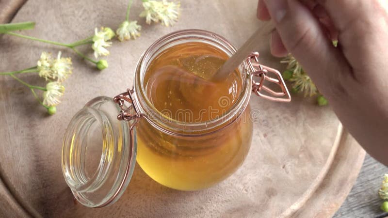 κινούμενη ξύλινη σταγόνα σε ένα βάζο μέλι με φρέσκα λινά άνθη την άνοιξη απόθεμα βίντεο