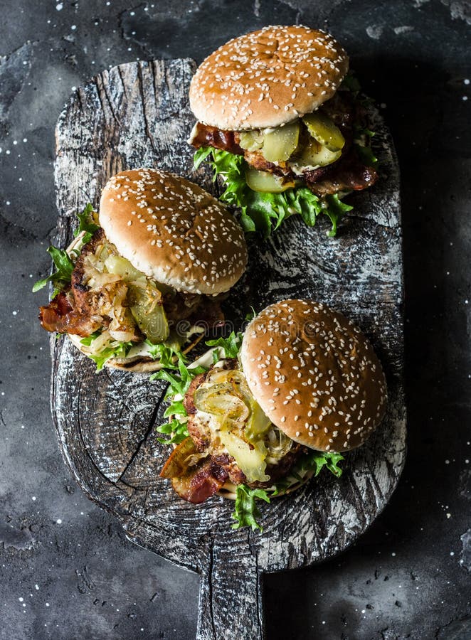 Κλασικό σπιτικό burger με cutlet χοιρινού κρέατος, μπέϊκον, τουρσιά, τηγάνισε τα κρεμμύδια και τη σάλτσα μουστάρδας μαγιονέζας στ στοκ φωτογραφία με δικαίωμα ελεύθερης χρήσης Κλασικό σπιτικό burger με cutlet χοιρινού κρέατος, μπέϊκον, τουρσιά, τηγάνισε τα κρεμμύδια και τη σάλτσα μουστάρδας μαγιονέζας στ στοκ φωτογραφία με δικαίωμα ελεύθερης χρήσης