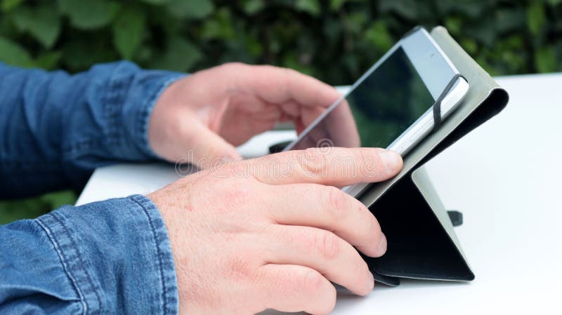 Κλείσιμο ενός ανθρώπου με χρήση tablet στον κήπο στοκ εικόνα