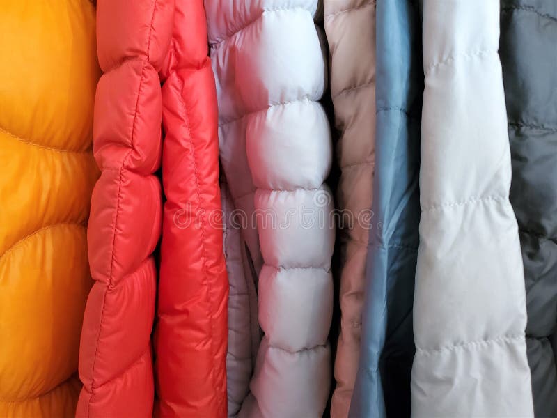 Parallel vertical sleeves of down polyester filled colorful fabrics aligned closely together.  Horizontal tapers of stitching align from one coat to another. Parallel vertical sleeves of down polyester filled colorful fabrics aligned closely together.  Horizontal tapers of stitching align from one coat to another