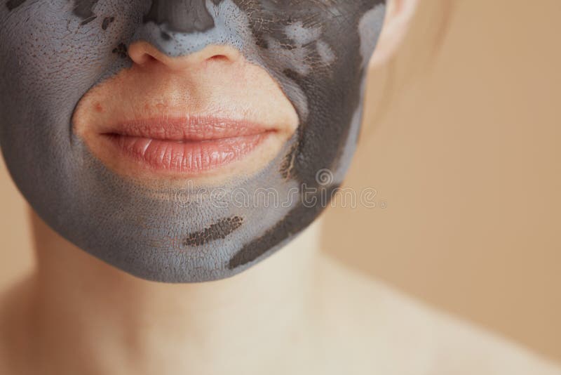κλείσιμο στη μεσήλικη γυναίκα με μάσκα προσώπου σε μπεζ φόντο