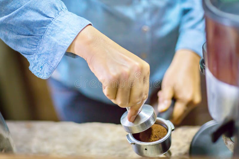 Κλείστε επάνω Barista πιέζει τον επίγειο καφέ χρησιμοποιώντας την πλαστογράφηση στοκ εικόνες με δικαίωμα ελεύθερης χρήσης Κλείστε επάνω Barista πιέζει τον επίγειο καφέ χρησιμοποιώντας την πλαστογράφηση στοκ εικόνες με δικαίωμα ελεύθερης χρήσης