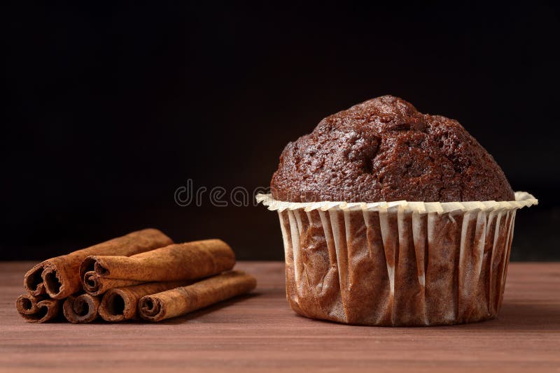 Κλείστε επάνω εύγευστο muffin σοκολάτας με τα ραβδιά κανέλας σε έναν ξύλινο πίνακα στο μαύρο κλίμα Διάστημα για το κείμενο στοκ φωτογραφίες με δικαίωμα ελεύθερης χρήσης Κλείστε επάνω εύγευστο muffin σοκολάτας με τα ραβδιά κανέλας σε έναν ξύλινο πίνακα στο μαύρο κλίμα Διάστημα για το κείμενο στοκ φωτογραφίες με δικαίωμα ελεύθερης χρήσης
