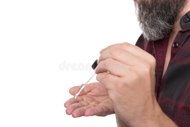 Κλείστε επάνω, πετρέλαιο γενειάδων μείωσης ατόμων στο χέρι του, προϊόν προσοχής γενειάδων για το hipster στοκ φωτογραφία
