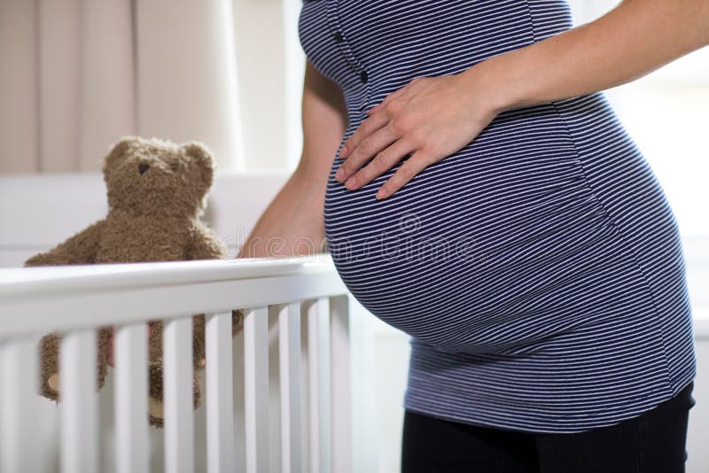 Κλείστε επάνω της εγκύου γυναίκας που βάζει Teddy αντέχει στην κούνια σε Nurser στοκ φωτογραφίες με δικαίωμα ελεύθερης χρήσης Κλείστε επάνω της εγκύου γυναίκας που βάζει Teddy αντέχει στην κούνια σε Nurser στοκ φωτογραφίες με δικαίωμα ελεύθερης χρήσης