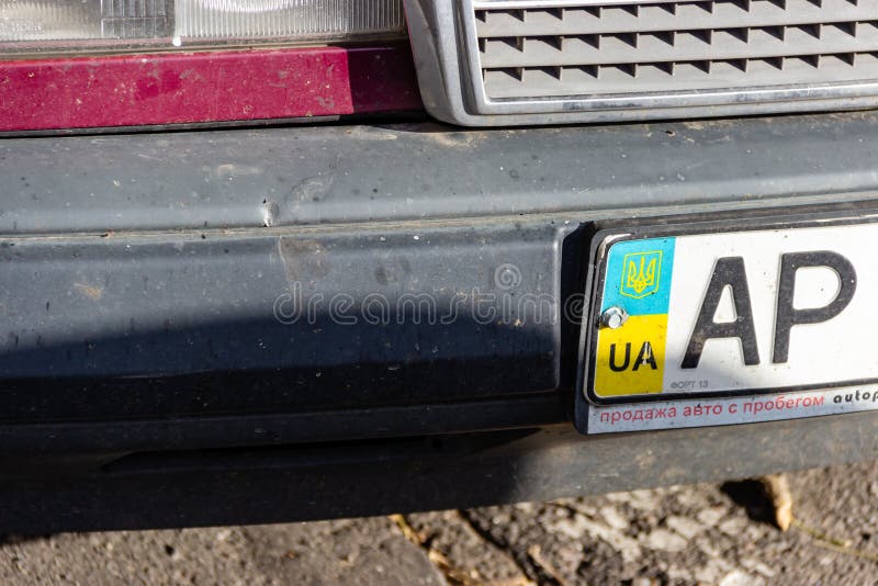 DNIPRO, UKRAINE - NOVEMBER 1, 2018: Close up of the Ukrainian car license plate on the bumper. National emblem on background of flag colors. Advertisement below for a dealer selling used cars. DNIPRO, UKRAINE - NOVEMBER 1, 2018: Close up of the Ukrainian car license plate on the bumper. National emblem on background of flag colors. Advertisement below for a dealer selling used cars