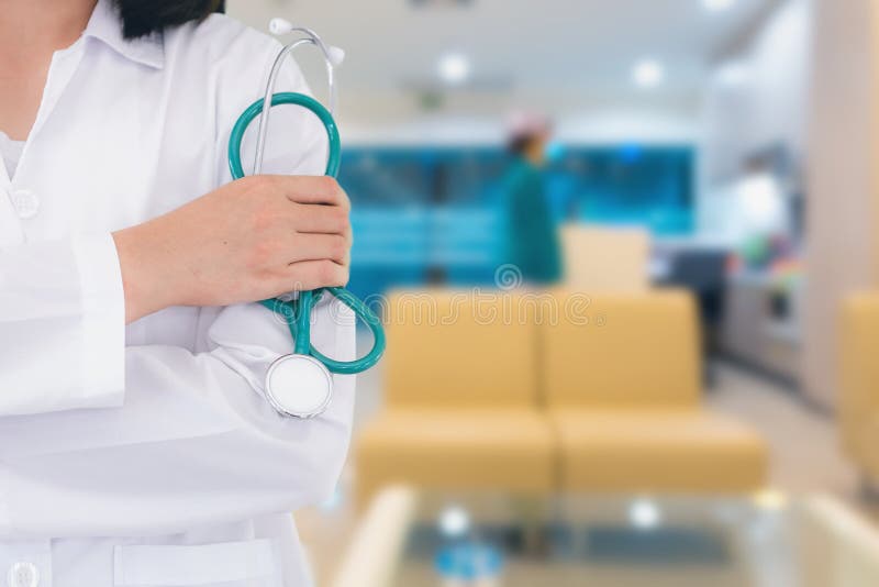 Κλείστε επάνω το πορτρέτο της θηλυκής μόνιμης τοποθέτησης γιατρών μπροστά από το γραφείο νοσοκομείων στοκ φωτογραφίες