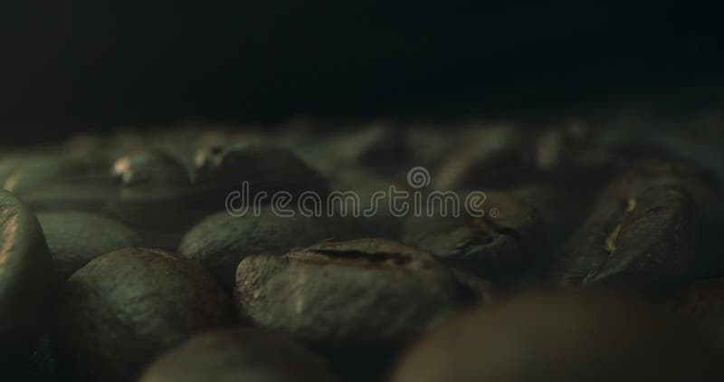 κλειστό στιγμιότυπο φρύξης κόκκων καφέ που έχει γυριστεί σε ένα σκούρο κλειδί ο καπνός που προέρχεται από την φρύξη κόκκων καφέ. η