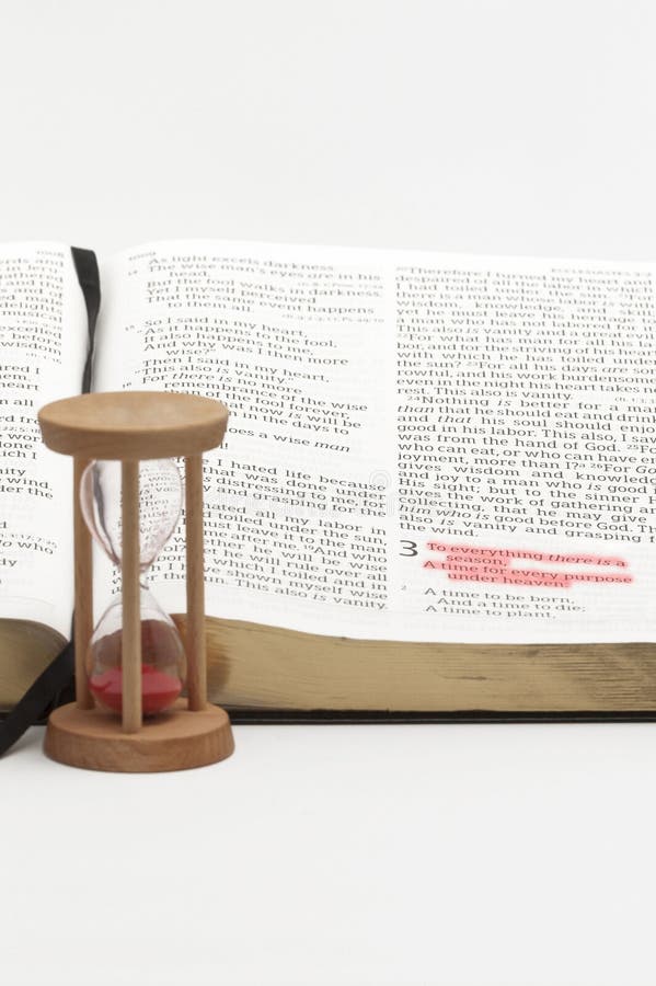 Hourglass and open bible on the book of Ecclesiastes with selective focus on verse 1 of chapter 3 highlighted in red. Isolated on white background. Hourglass and open bible on the book of Ecclesiastes with selective focus on verse 1 of chapter 3 highlighted in red. Isolated on white background.