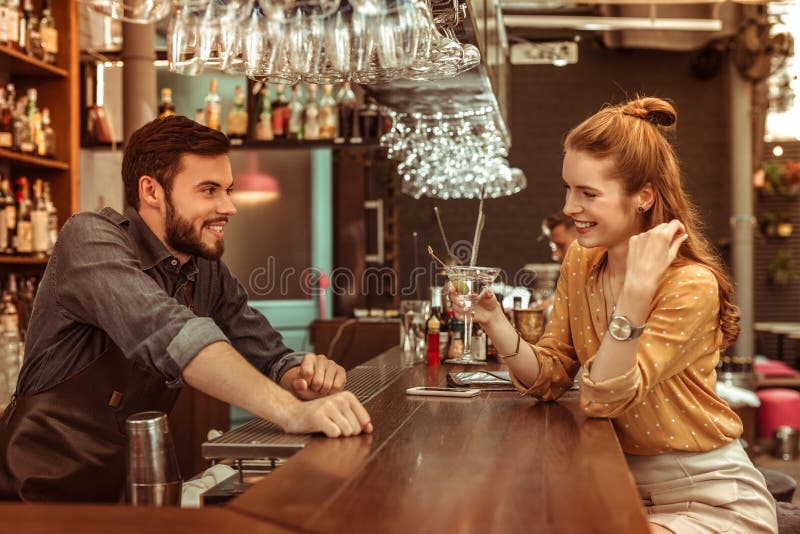 Κοκκινομάλλης γυναίκα που μιλά bartender κρατώντας ένα κοκτέιλ στοκ εικόνες Κοκκινομάλλης γυναίκα που μιλά bartender κρατώντας ένα κοκτέιλ στοκ εικόνες