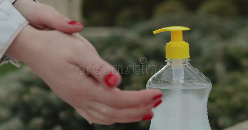 κοντά θηλυκά χέρια σπρώχνουν απολυμαντικό και απολυμαντικά στο εξωτερικό φιλμ μικρού μήκους